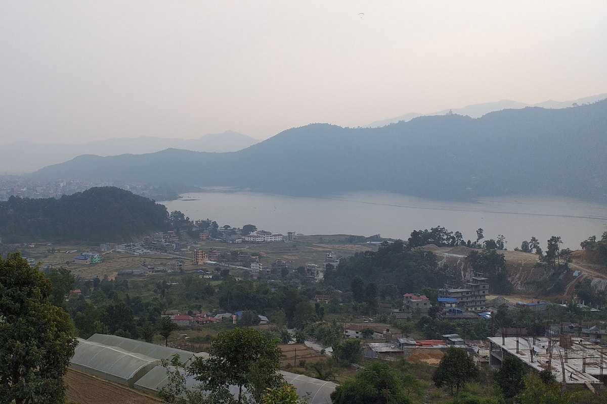A panoramic view of a hilly town with a river, buildings, and greenery.