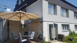 A patio with a table and chairs, a large umbrella, and a clothesline. - Gästehaus Udligenswil (Udligenswil)