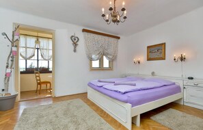 A bedroom with a bed, a window with curtains, a chandelier, a bedside table, and a dresser. - Luxurious home in Ludbreg (Ludbreg)