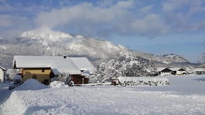 Un pueblo cubierto de nieve con casas de madera tradicionales, un telón de fondo montañoso y un cielo despejado.