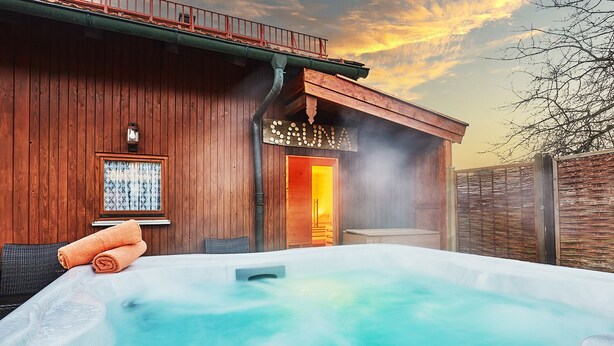 Una cabaña de madera con un jacuzzi, una ventana con cortinas y una puerta que da a un espacio interior.