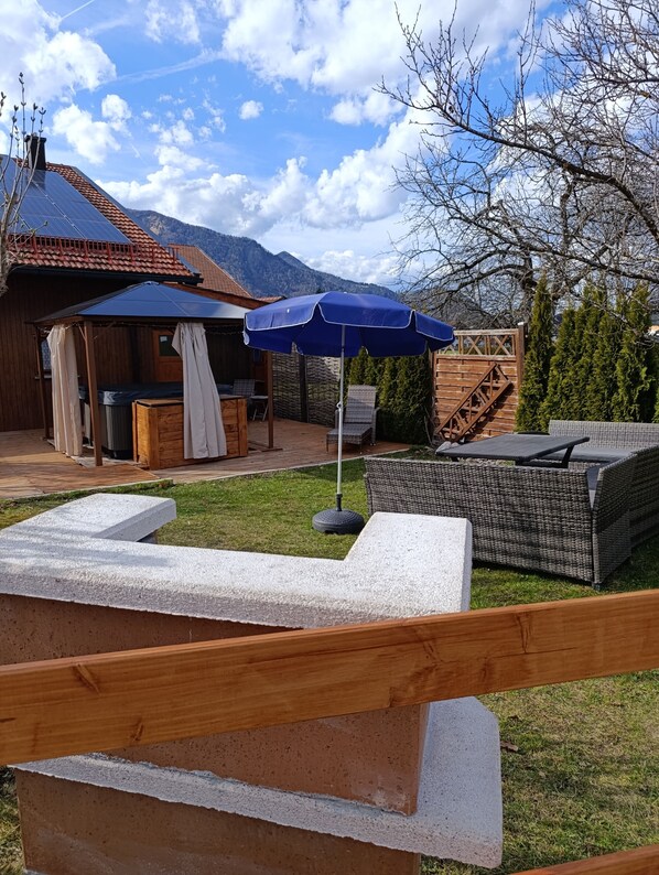Una cabaña de madera con un patio, mobiliario exterior y vistas a las montañas.