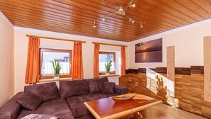 Una sala de estar acogedora con un sofá seccional marrón, una mesa de centro de madera y vista a una escalera de madera.