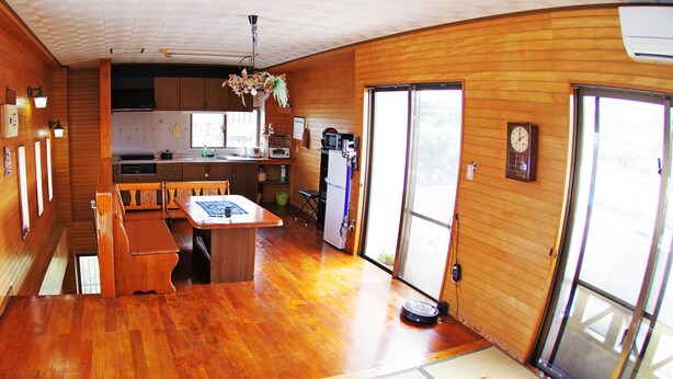 Una cocina amplia con armarios de madera, un comedor con mesa y sillas, y un ventanal corredero que da a un balcón.