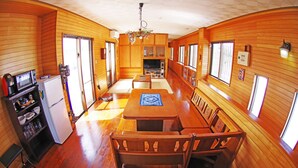 Una cocina compacta con paredes de madera, un comedor con mesa y sillas, y un refrigerador.