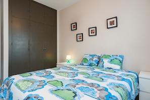 Ein Schlafzimmer mit Bett, Nachttisch, Lampe und Kleiderschrank.