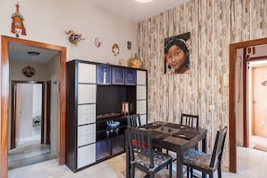 Ein Essbereich mit Holztisch und -stühlen, einer Schubladenschrank und einer Wand mit Muster.