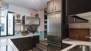 Een moderne keuken met een roestvrijstalen koelkast, donkere kasten en een betegelde spatwand.