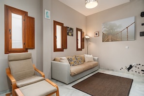 Ein Wohnzimmer mit Sofa, Sessel, Teppich und einem Gemälde einer Brücke.