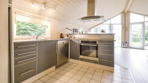 A modern kitchen with a built-in dishwasher, oven, and a large window providing natural light.