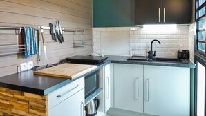 A modern kitchen with wooden cabinetry, a black countertop, and a stainless steel sink. - Le Domaine de Jade Chalet Amélie (saint andre)