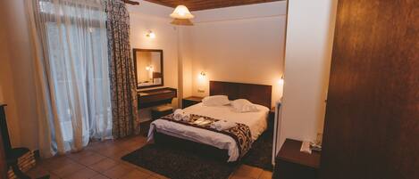 A bedroom with a bed, bedside tables, a mirror, and a wooden ceiling.