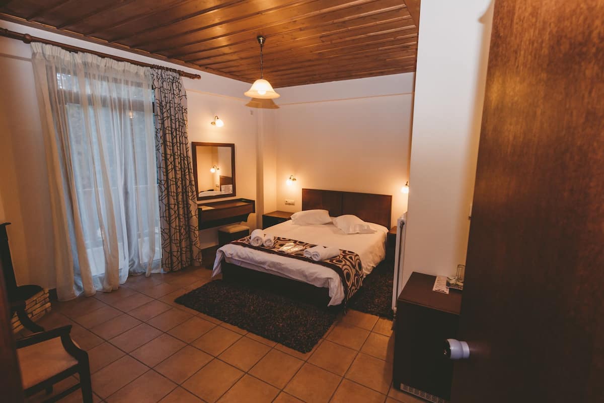 Un dormitorio con cama, mesitas de noche, un espejo y techo de madera.