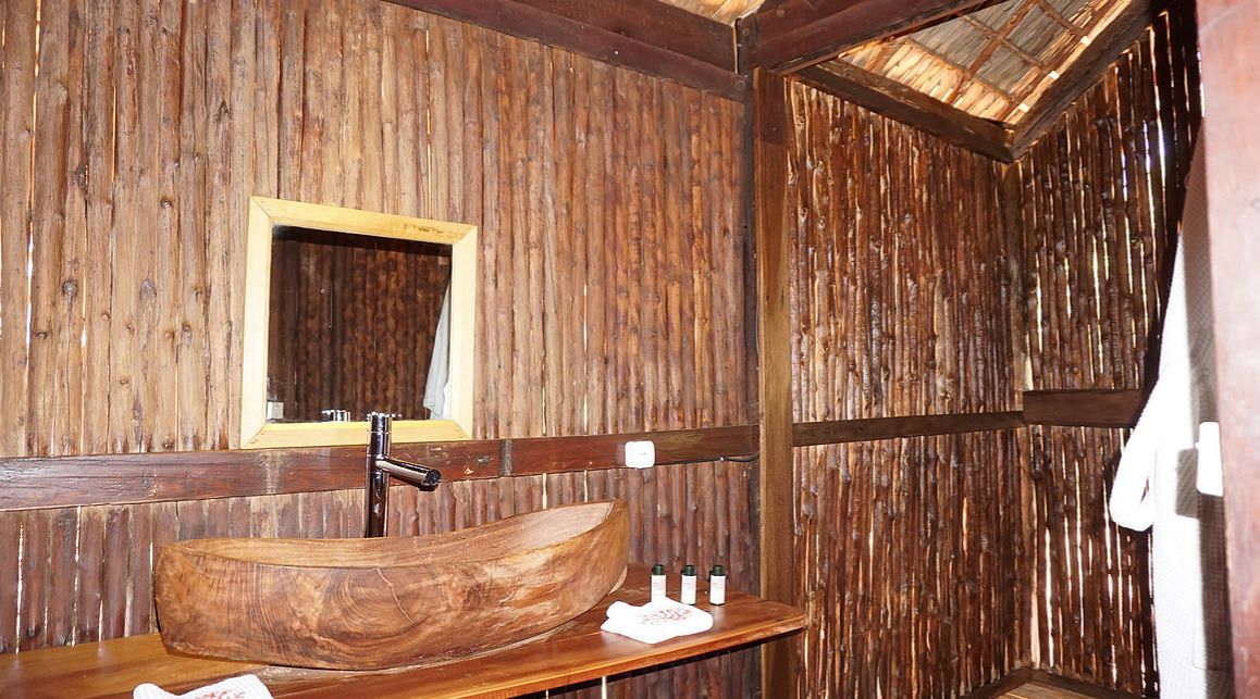Ein rustikales Badezimmer aus Holz mit einem Holzbachttisch, einem Spiegel und einem Ablagebereich für Toilettenartikel.