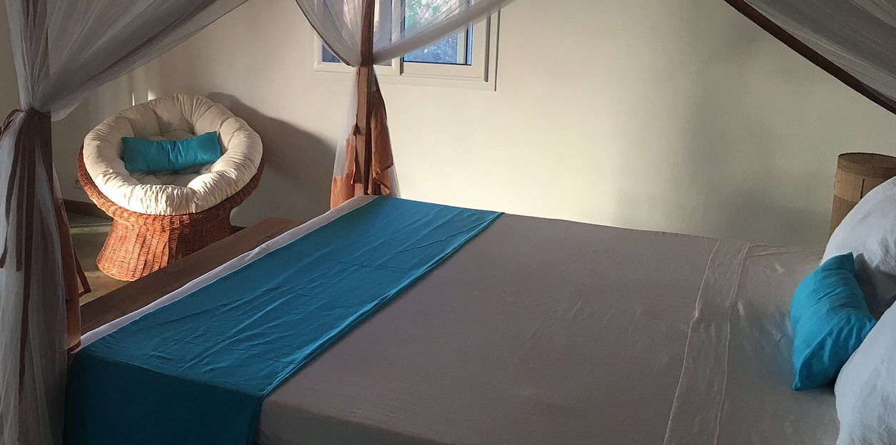 A bedroom with a bed, a chair, and a window.