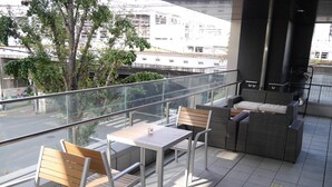 A balcony with a table and chairs, a sofa, and a fan. - HEARTS Capsule Hotel & Spa HAKATA (Fukuoka)