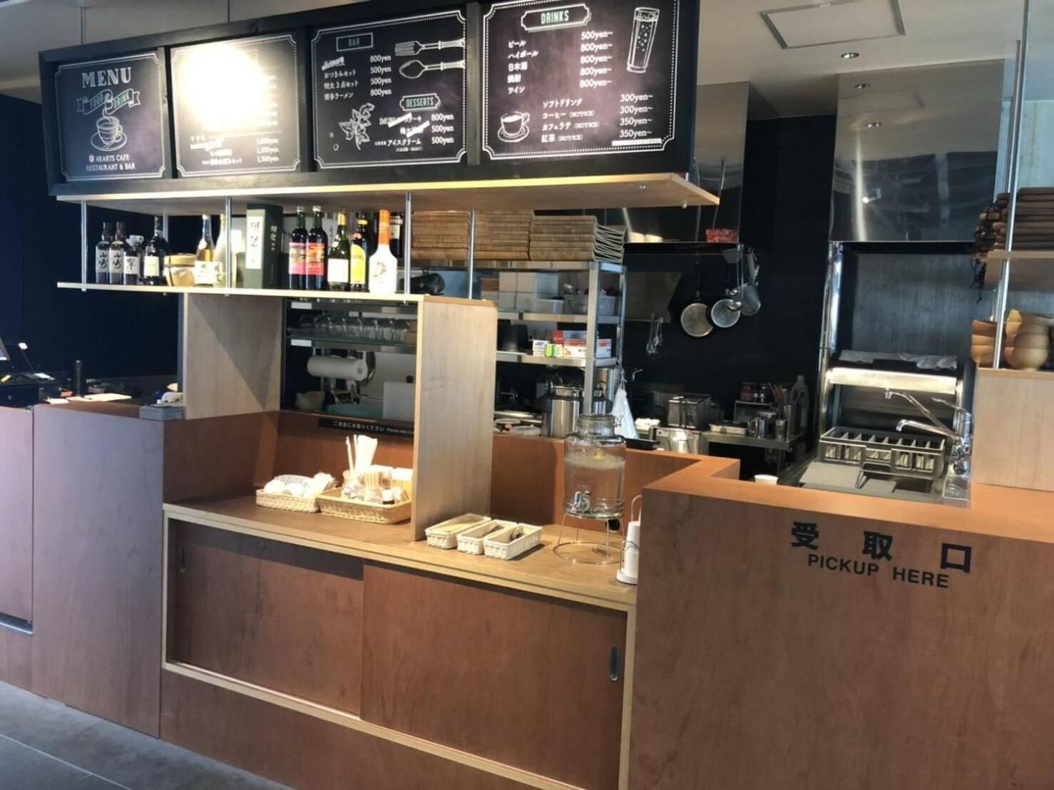 A restaurant counter with a menu board, a beverage display, and a pickup area.