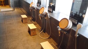 A modern bathroom with multiple wooden basins and a tiled floor. - HEARTS Capsule Hotel & Spa HAKATA (Fukuoka)