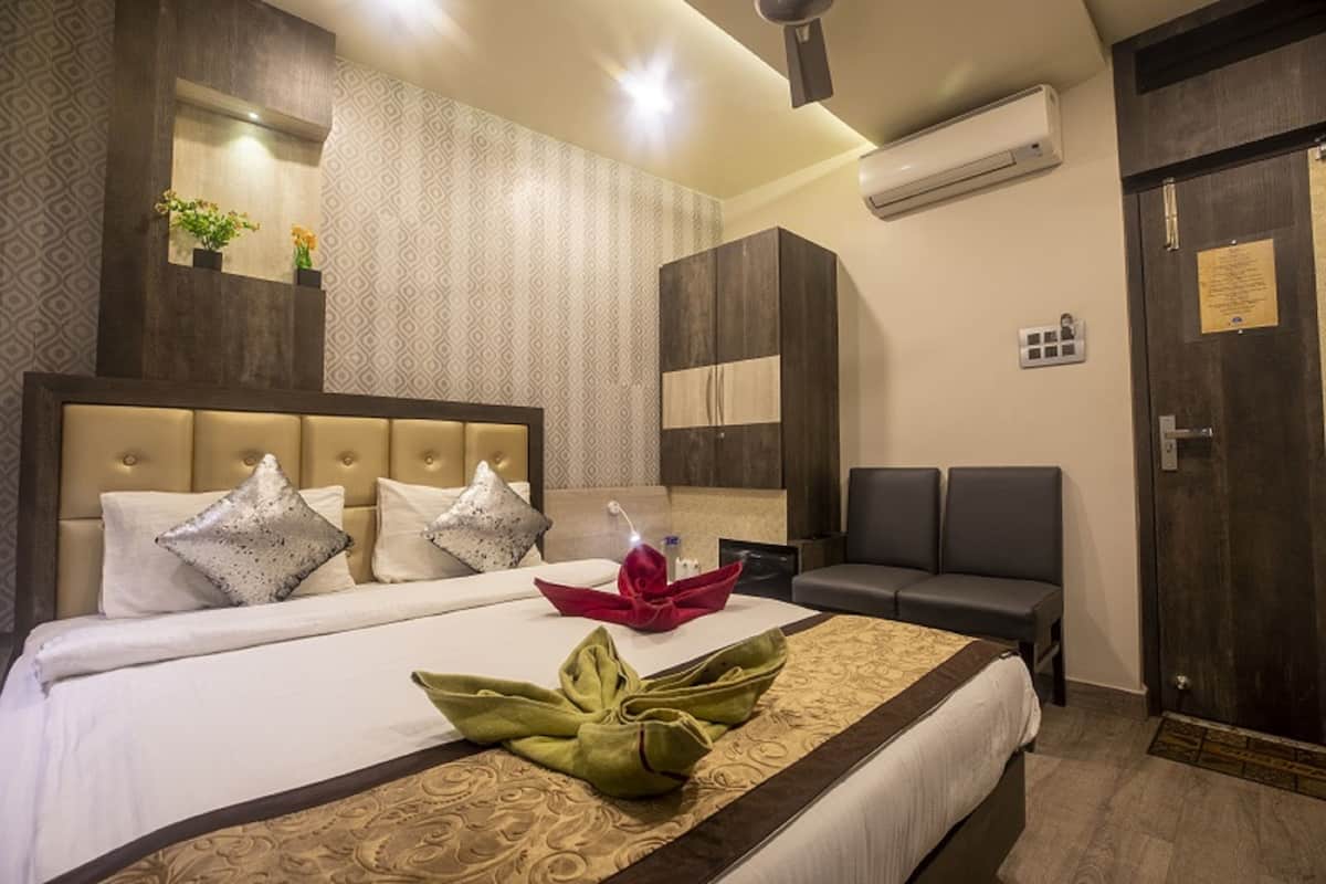 A hotel room with a large bed, two bedside tables, a seating area, and a wardrobe.