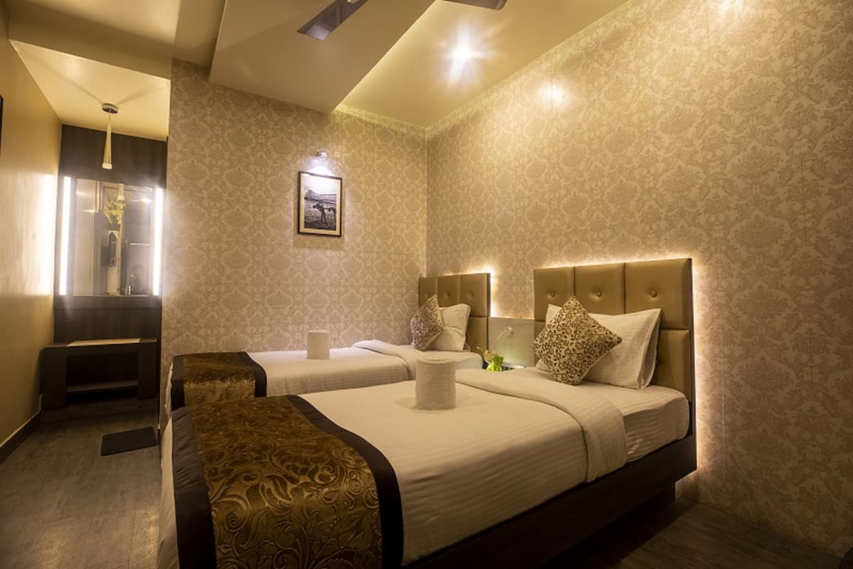 A hotel room with two beds, a sitting area, and a framed picture on the wall.
