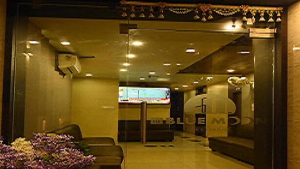 A hotel lobby with a reception desk, seating area, and a large screen displaying content. - Nu Blue Moon Guest House (Howrah)