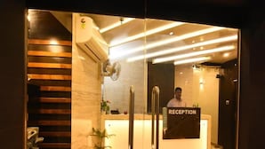 A reception area with a glass door, a reception desk, and a person standing behind it. - Nu Blue Moon Guest House (Howrah)