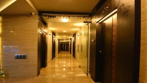 A hotel hallway with a polished marble floor, dark wooden doors, and recessed lighting. - Nu Blue Moon Guest House (Howrah)