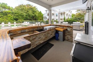 Un espace cuisine extérieur doté d’un plan de travail en pierre, d’un évier et d’un barbecue.