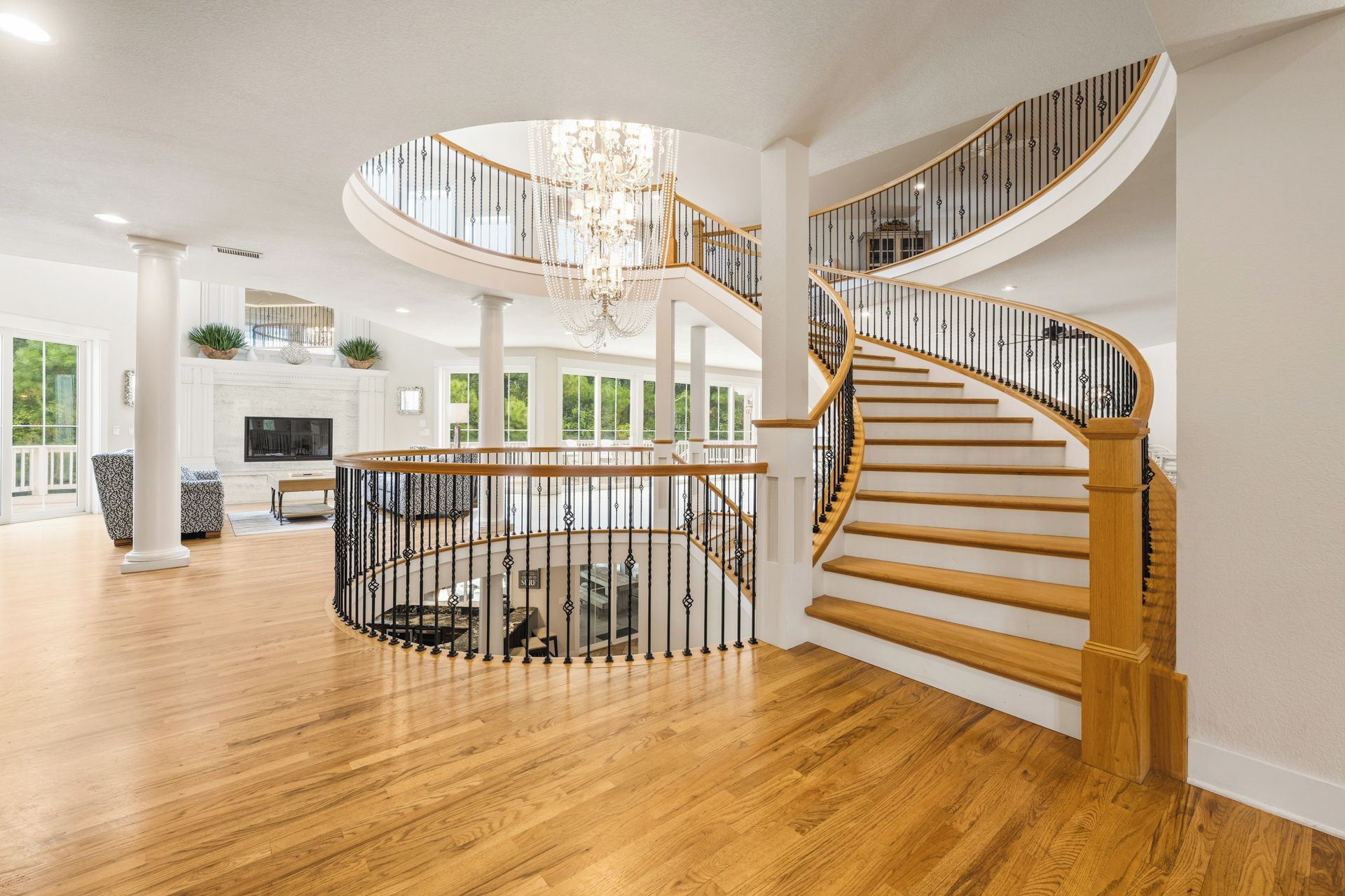 A spacious interior with a grand spiral staircase, a chandelier, and a fireplace.