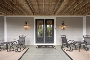 A covered porch with two doors, two wall-mounted lights, and a welcome mat.