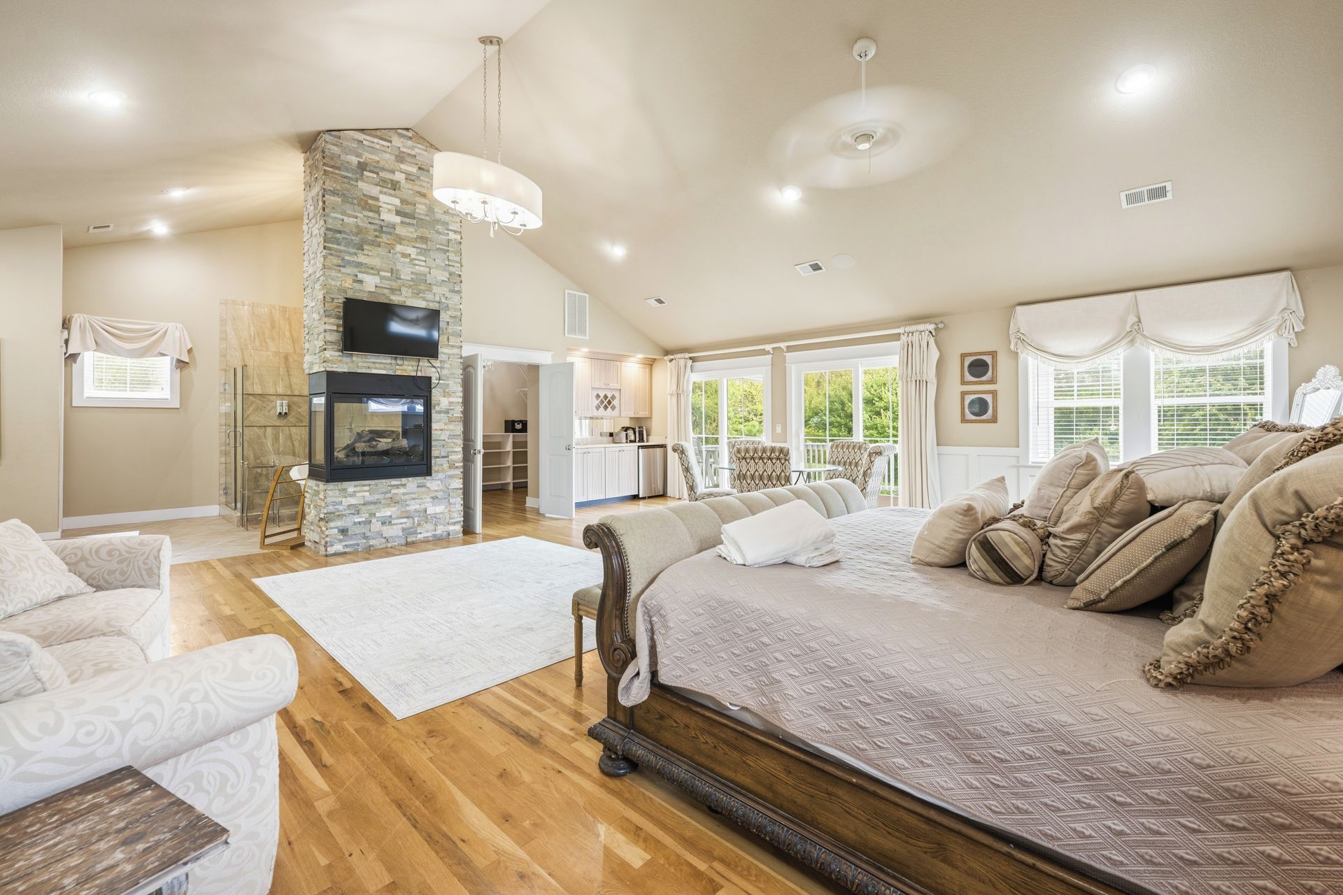 A spacious living area with a fireplace, a large bed with multiple pillows, and a dining area with chairs.