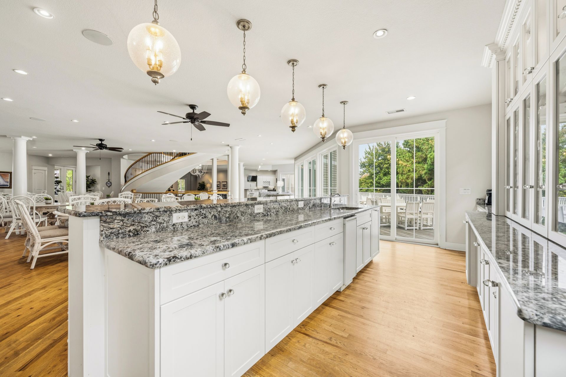A spacious kitchen with a large island, white cabinetry, and a wooden floor.