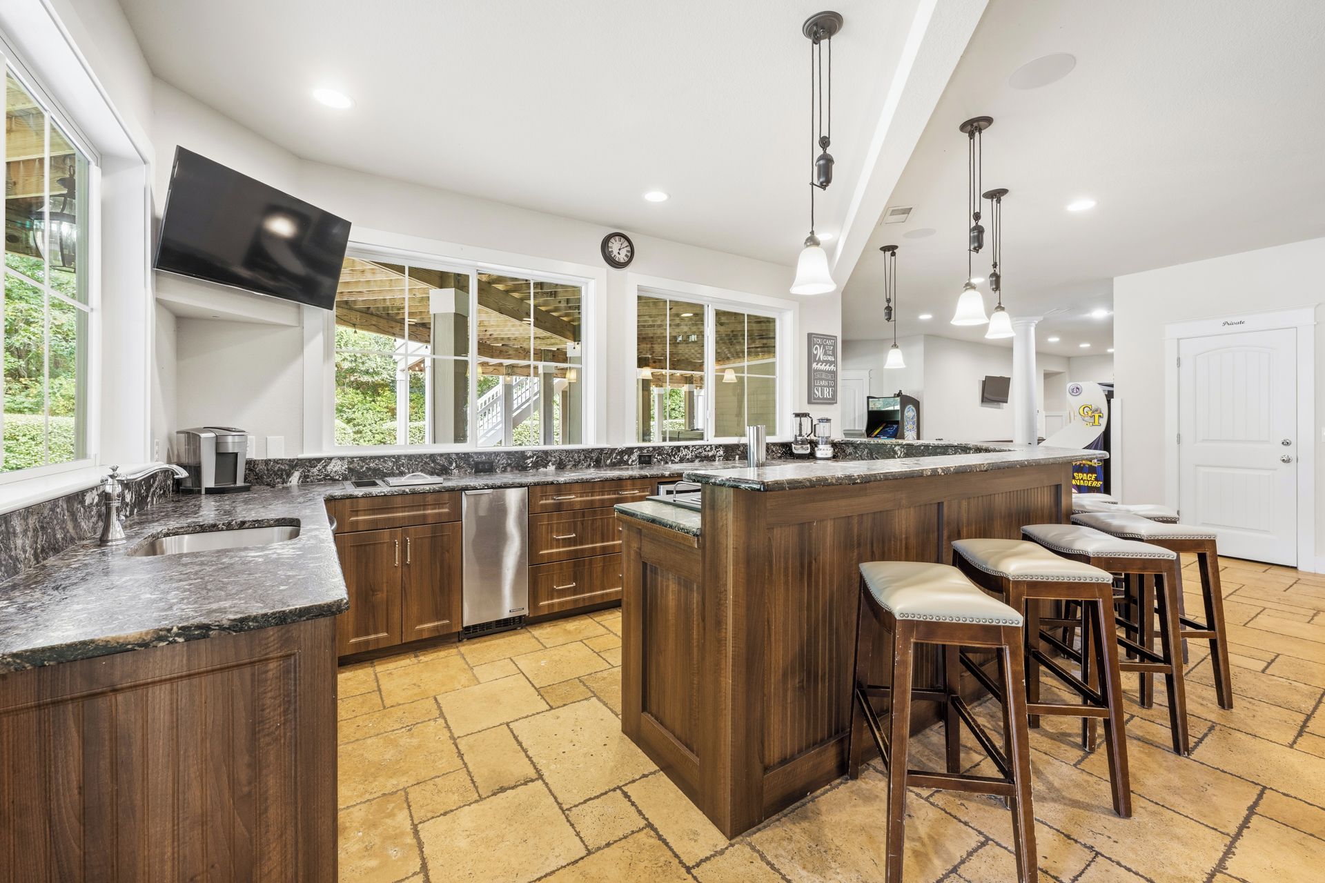 Una cocina moderna con una isla grande, taburetes de bar y un televisor montado en la pared.