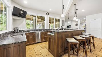 Una cocina moderna con una isla grande, taburetes de bar y un televisor montado en la pared.