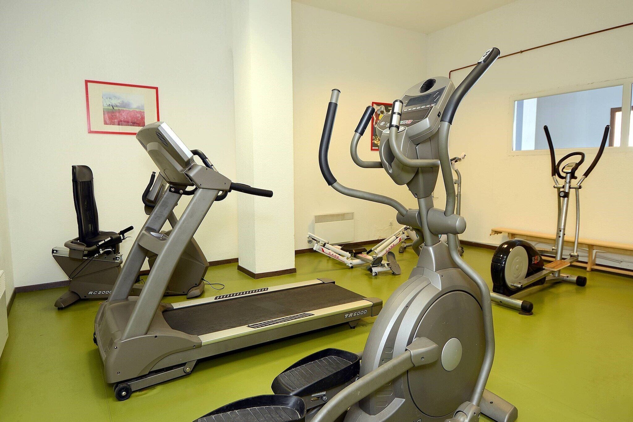 A gym with stationary bikes, treadmills, and a rowing machine.