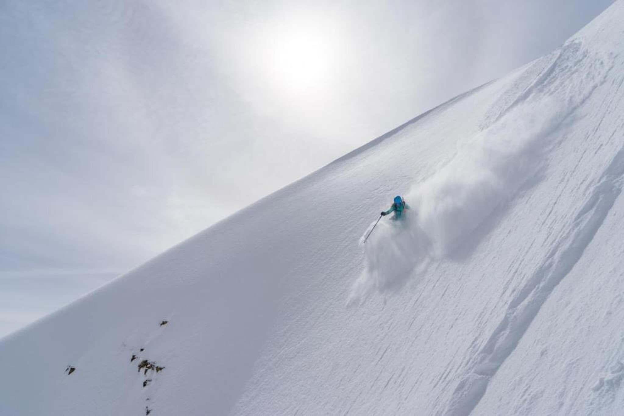 Eine Person fährt auf Skiern einen schneebedeckten Hang hinab.
