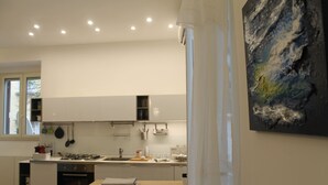 Una cocina moderna con armarios blancos, una isla de madera y un cuadro en la pared.