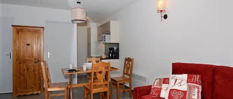 A compact living space with a dining area, a red sofa, and a kitchenette.