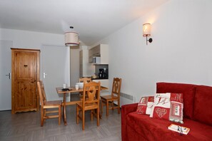 Ein gemütlicher Wohnbereich mit Essplatz, einem roten Sofa und einer Küchenzeile.