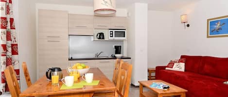 A compact living space with a dining area, kitchen, and a red sofa.