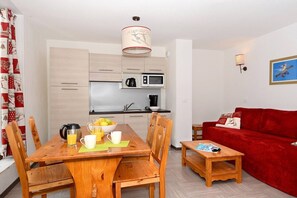 A compact living space with a dining area, kitchen, and a red sofa.