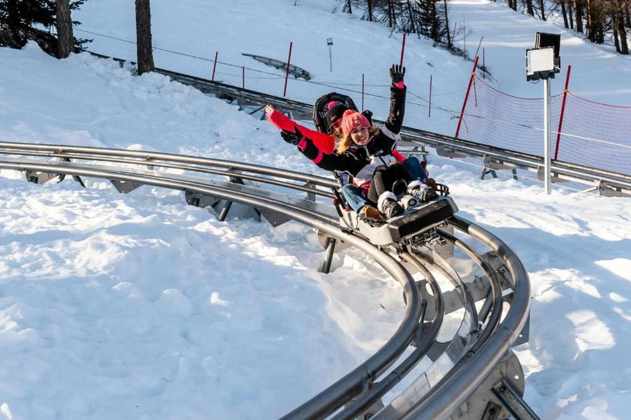 A person sledding down a snow-covered slope with metal railings.