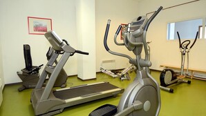 Une salle de sport équipée de vélos d’appartement, de tapis de course et d’un appareil d’aviron.