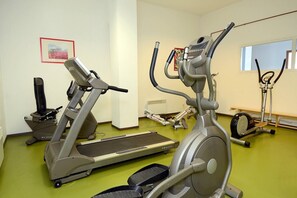 Ein Fitnessstudio mit Ergometer, Laufbändern und einem Rudergerät.