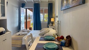 Ein Hotelzimmer mit einem Bett, einem Esstisch mit Tellern, einer Lampe und einem Bild an der Wand.