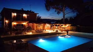 Ein zweigeschossiges Haus mit Swimmingpool, Sitzbereich im Freien und einer gut beleuchteten Terrasse.