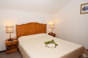 A single bed with a wooden headboard, two bedside tables with lamps, and a framed picture on the wall. - Slopeside Chalet in Vars (VARS)