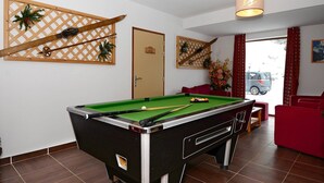 Et billardbord i et rum med en dør med teksten 'WC 3' og en rød sofa.