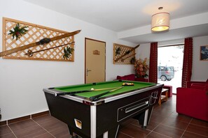 A pool table in a room with a door labeled 'WC 3' and a red couch. - Slopeside Chalet in Vars (VARS)