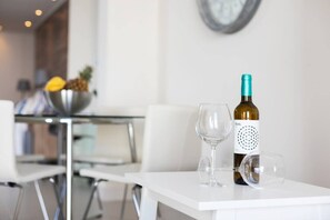 Una botella de vino y dos copas sobre una mesa blanca en un comedor moderno.